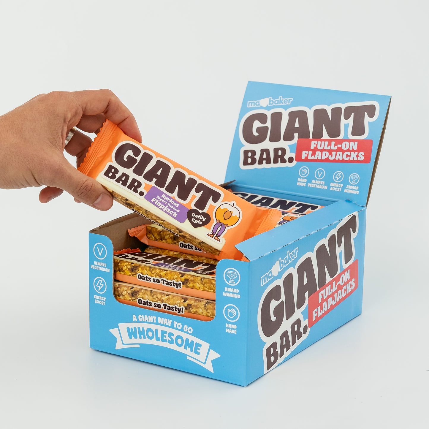A hand taking an Apricot Yoghurt Topped Giant Bar out of a box of Giant Bars