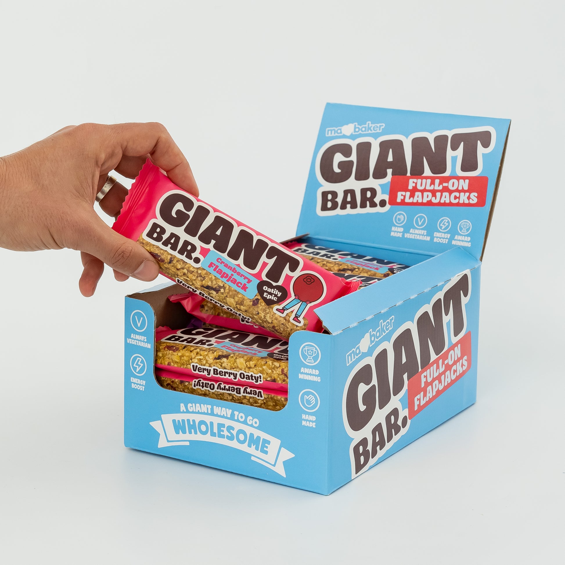 A hand taking a Cranberry Giant Bar from a box of Giant Bars