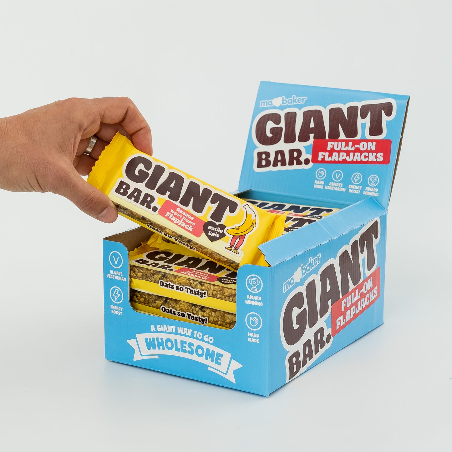 A hand taking a Banana Yoghurt Topped Giant Bar out of a box of Giant Bars