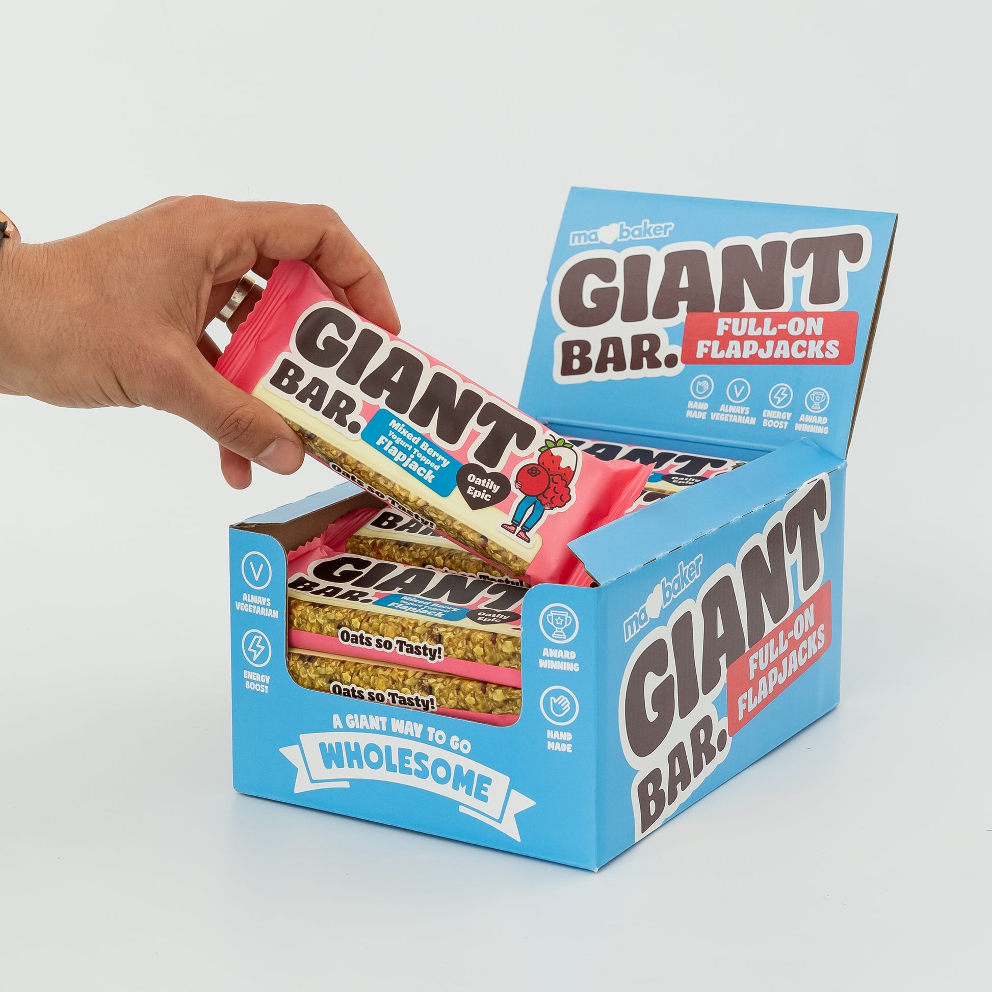 A hand taking a Mixed Berry Yoghurt Topped Giant Bar out of a box of Giant Bars