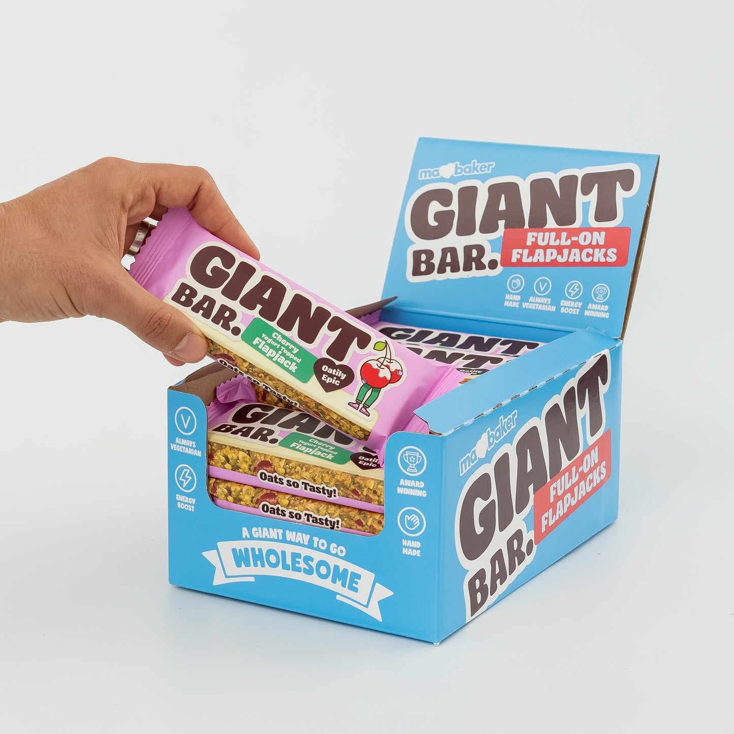 A hand taking a Cherry Yoghurt Topped Giant Bar out of a box of Giant Bars