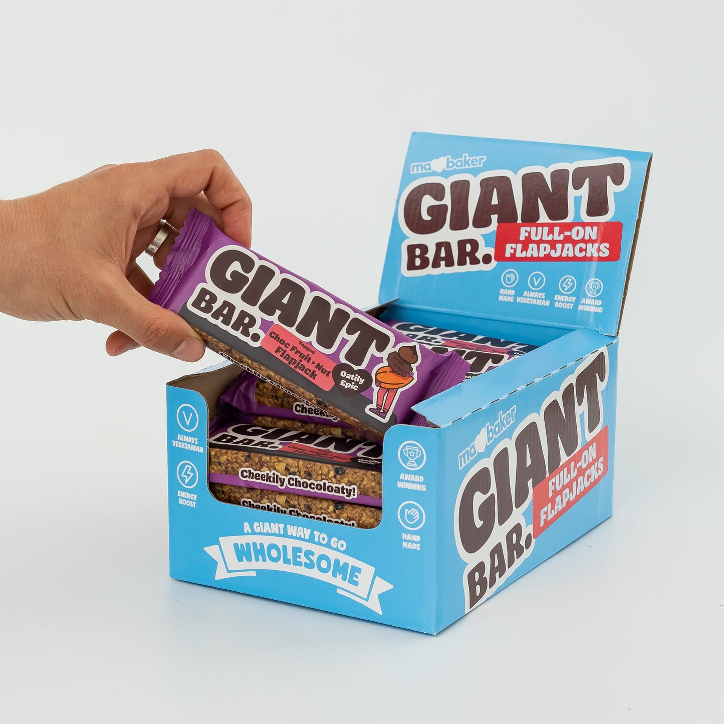 A hand taking a Topped Choc Fruit + Nut Giant Bar out of a box of Giant Bars