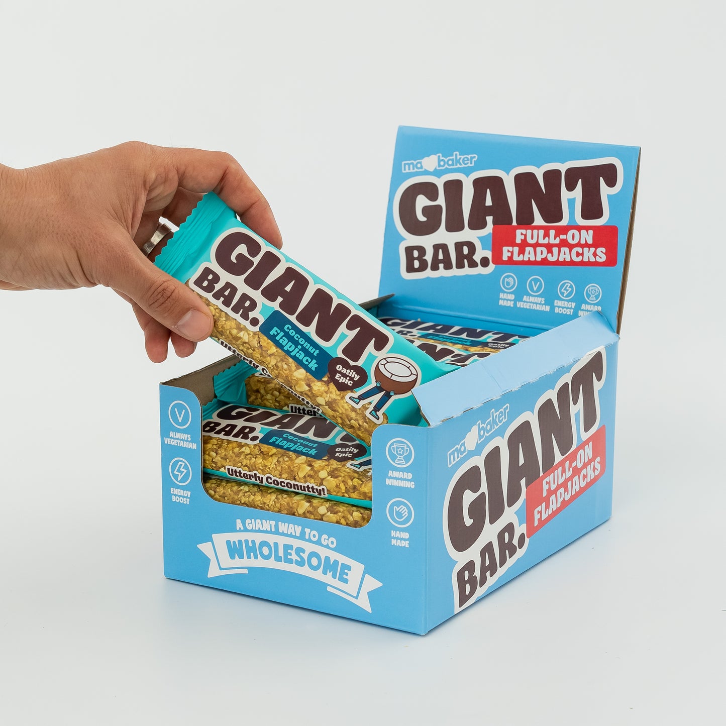 A hand taking a Coconut Giant Bar from a box of Giant Bars